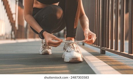 Close up - Running runner woman tying laces sneakers shoes for summer run in the city at sunset. Jogging girl exercise motivation health and fitness exercise, lifestyle. - Powered by Shutterstock