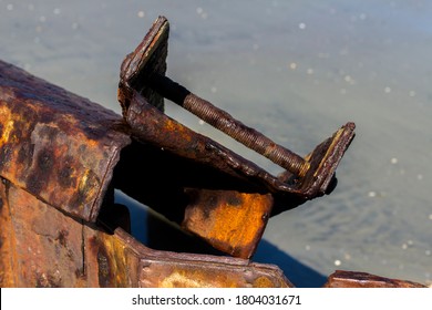 Close Up Of A Rusted Sea Groin Cover Broken And Bent Backwards And Extending Into A Pool Of Sea Water On Bright Daylight 