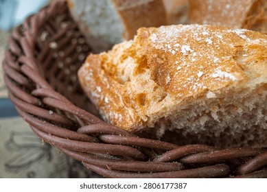 Close up of rustic crusty bread pieces in a woven basket, with flour dusting and warm bakery texture, perfect for food, breakfast, homemade cooking, and fresh artisan loaf themes.