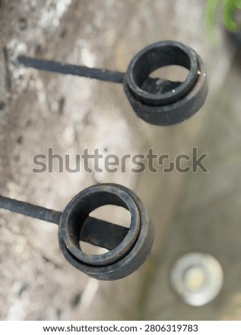 Close up of rustic wrought iron candle holder mounted on stone wall. Vintage industrial decor and home interior concept.