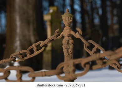 Close up of rusty chains. Graveyard or cemetry with headstones in winterlandscape with snow. Maatschappij van Weldadigheid Unesco World Heritage at Frederiksoord Netherlands. 