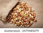 close up of sack of mixed nuts on wooden table, top view