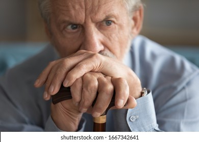 Close up of sad distressed mature 60s man with walking stick look in distance thinking pondering, upset lonely old male with wooden cane lost in thoughts yearning or missing, elderly solitude concept