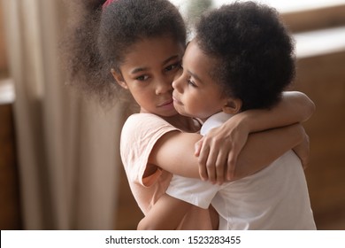 Close up sad elder african american sister hugging, holding, cuddling smaller upset offended cute brother, feeling sorry, warm friendly peaceful relationship between children, adoption concept. - Powered by Shutterstock