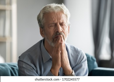 Close Up Sad Faithful Mature Man With Closed Eyes Praying With Hope Alone, Religious Upset Older Senior Male Holding Hands Together In Prayer, Begging, Asking For Help, Saying Worship