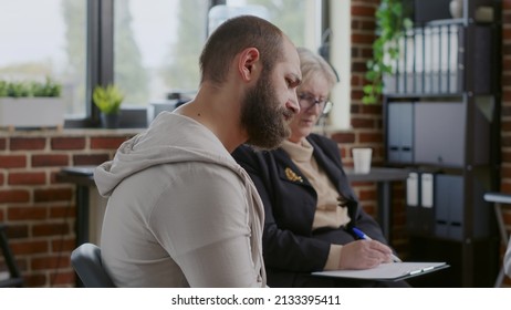 Close Up Of Sad Man Sharing Addiction Story With Group Of People At Aa Rehab Meeting. Person Making Confession About Mental Health In Front Of Psychologist At Therapy Session Program.