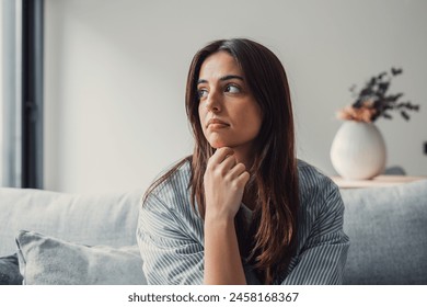 Close up of sad pensive millennial woman sit alone thinking about relationships personal problems, upset thoughtful young female lost in thoughts feel lonely depressed pondering or mourning at home