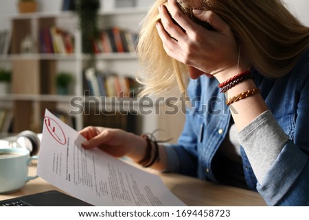 Close up of sad student complaining about failed exam sitting on a desk at home at night