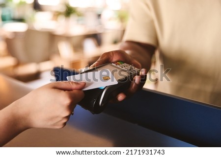 Close In Of Sales Assistant In Retail Shop With Customer Paying Using Contactless Payment Credit Card NFC