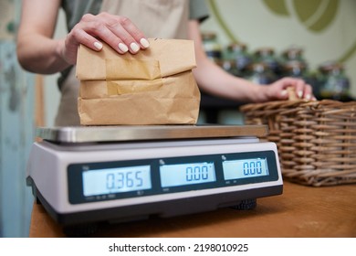 Close Up Of Sales Assistant In Sustainable Plastic Free Grocery Store Weighing Goods In Paper Bag On Digital Scales - Powered by Shutterstock