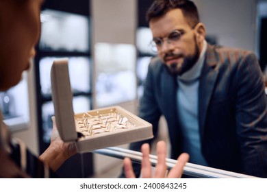 Close up of saleswoman showing rings to a man at jewelry store. - Powered by Shutterstock