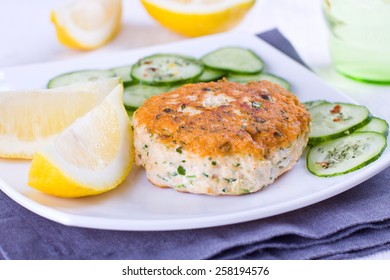 Close Up Of A Salmon Patty Served With Cucumber And Lemon