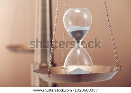 close up of sand glass in the scale of justice.