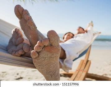 Close Up Of Sandy Feet Of Couple In A Hammock On The Beach