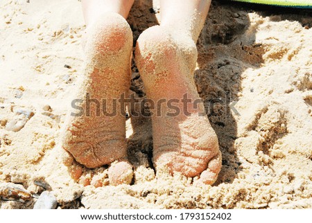 Close up child’s sandy feet on beach