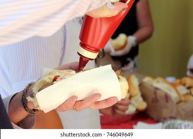 Close Up Of Sausage In A Roll, With Sauce Being Added, At A Sausage Sizzle