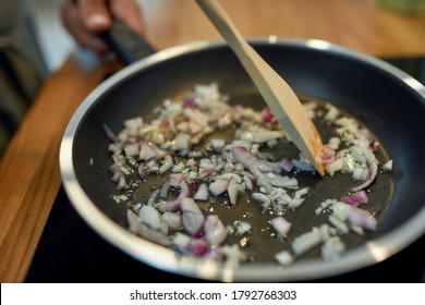 Close up of sauteed onion and garlic in the frying pan. Man preparing dinner. Cooking at home concept. Selective focus. Horizontal shot
