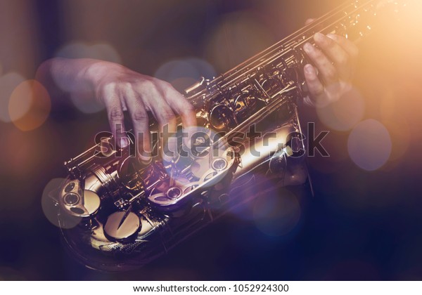 close up of saxophone player plays\
saxophone  with music concert light and Bokeh on\
stage