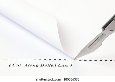 Close Up Of A Scalpel Cutting Along A Dotted Line On A Sheet Of White Paper.