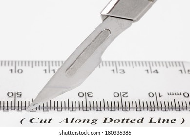 Close Up Of A Scalpel Cutting Along A Dotted Line On A Sheet Of White Paper, With A Ruler.