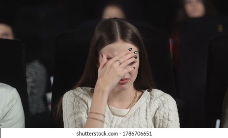 Close Up Of A Scared Young Woman Using Her Hands To Cover Her Face While Watching A Scary Movie.