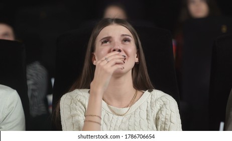 Close Up Of A Scared Young Woman Using Her Hands To Cover Her Face While Watching A Scary Movie.