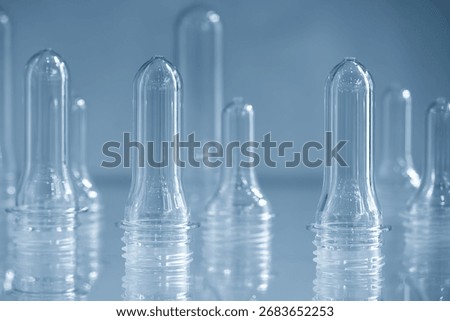 Close up scene of group of preform shape of PET bottle products in the light blue scene. The raw material for plastic bottle manufacturing process.