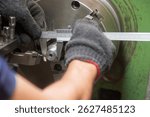 Close up scene the machine operator measuring diameter of turning parts by Vernier caliper. The parts measurement on turning machine by machine operator.