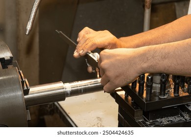 Close up scene the machine operator measuring dimension of metal shaft parts by Vernier caliper on lathe machine. The quality control on turning machine.  - Powered by Shutterstock