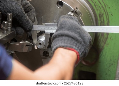 Close up scene the machine operator measuring diameter of turning parts by Vernier caliper. The parts measurement on turning machine by machine operator.