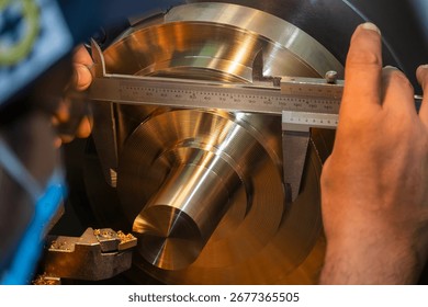 Close up scene the machine operator measuring dimension of metal shaft parts by Vernier caliper. The parts quality control by vernier caliper on turning machine by machine operator.