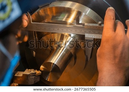 Close up scene the machine operator measuring dimension of metal shaft parts by Vernier caliper. The parts quality control by vernier caliper on turning machine by machine operator.