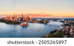 Close scenic aerial sunrise cityscape panorama of City of Sydney waterfront on shores of harbour by the Bridge.