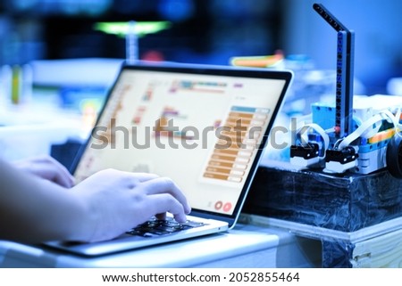 Close up of school child hands developing and programming lego robotics model on laptop in class. Kids STEM program, science and education background.