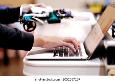 Close up of school student designing and programming robotic project - lego robot vehicle model on laptop. Kids STEM program, science, technology, innovation, creativity and education background.