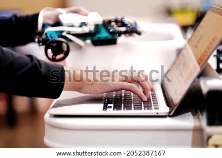 Close up of school student designing and programming robotic project - lego robot vehicle model on laptop. Kids STEM program, science, technology, innovation, creativity and education background.