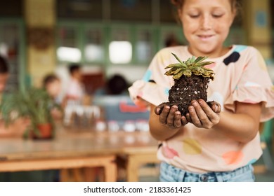 Close Up Of Schoolgirl Holding Plant During School Science Project In The Classroom. 