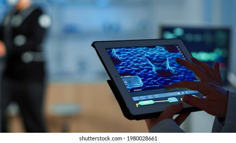 Close up of scientist analysing health informations in tablet while specialist sport supervises exercise of sportsman monitoring his physical endurance. Examining medical scan in notepad in laboratory - Powered by Shutterstock