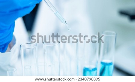 Close up of scientist is dropping blue liquid substance in science test tube in laboratory. Concept of science, biochemistry, chemical, diagnosis, biotechnology. Substance study analyzing experiment