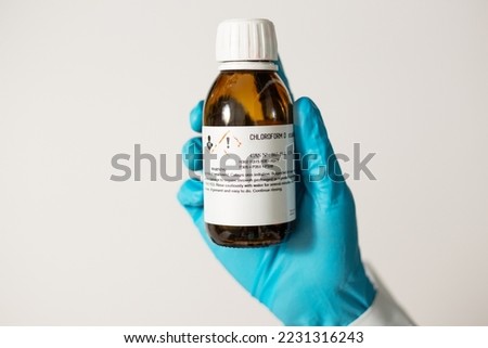 Close up of Scientist hand shows glass bottle of chloroform solvent with a label warning about toxicity. Chemical reagent in laboratory, caution for use.