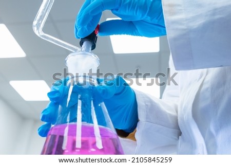 Close up scientist uses a titration method of analysis to study the chemical properties of the water sample. Scientist holding Erlenmeyer flask with pink solution