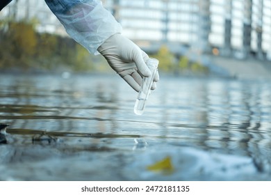 Close up of scientist with white glove holding test tube with water in his hand. Water pollution examine concept - Powered by Shutterstock