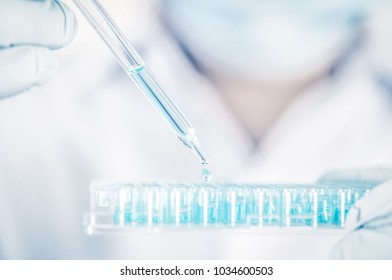Close up a scientist working in laboratory to analyze blue extracted of DNA  molecules in micro tube plate , clinical or science testing analysis concept - Shutterstock ID 1034600503
