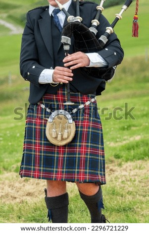 Close up of a Scottish bagpiper dressed in traditional kilt in the Highlands, Scotland