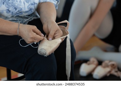 Close up of a seamstress sewing ribbons on used ballet pointes shoes - Powered by Shutterstock