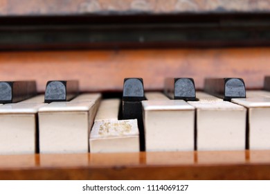 Close Up Section Of An Old Worn Out Traditional Piano Keyboard That Has A Permanently Dropped Piano Key With The White Covering Of The Piano Keys Peeling Off Showing The Old Glue Underneath.