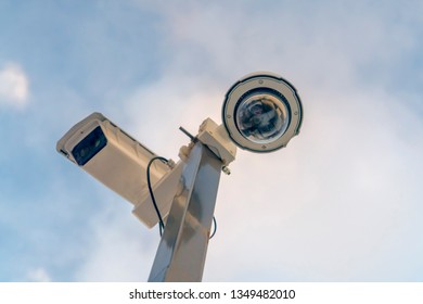 Close up of security cameras against cloudy sky