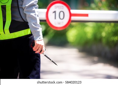 Close Up In A Security Guard With A Portable Wireless Transceiver , Entrance The Village On A Blurry Background