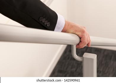 close up with selective focus of a business man's hand holding a hand rail while descending the stairs