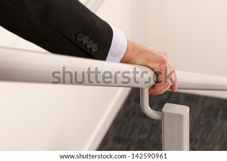 close up with selective focus of a business man's hand holding a hand rail while descending the stairs